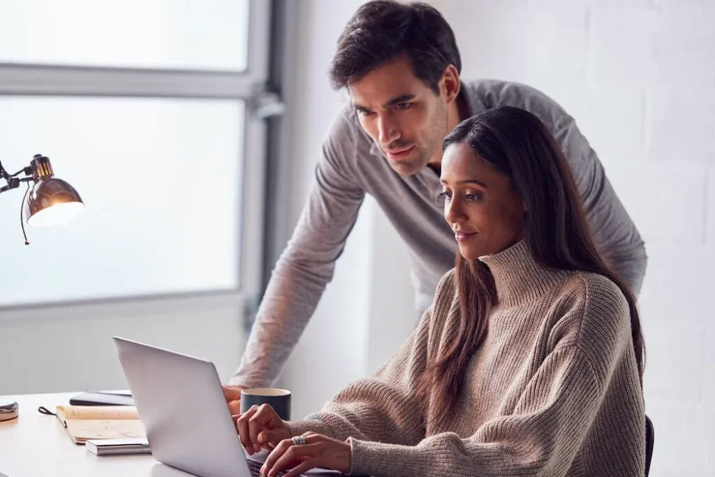 Two people reviewing information on a laptop at home