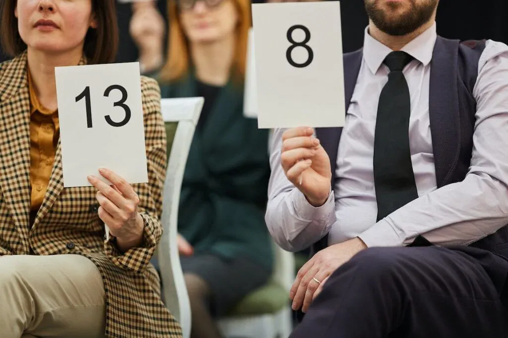 Registered bidders holding numbered paddles at a property auction