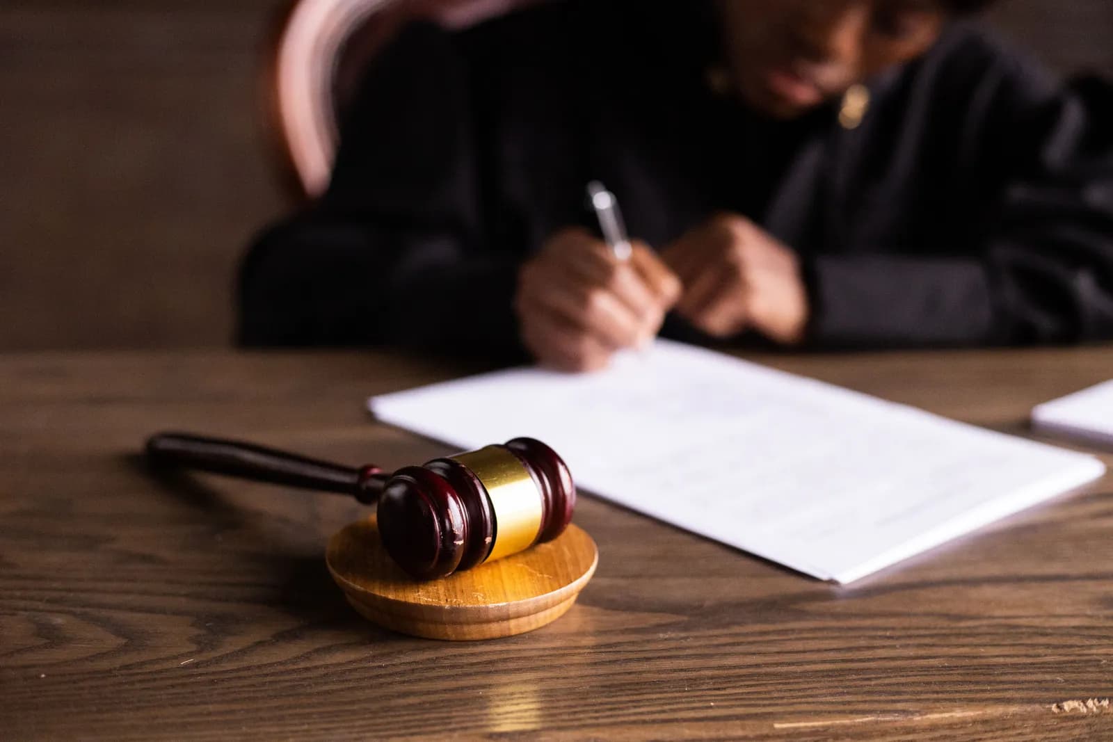 Gavel on a desk beside a person signing legal documents