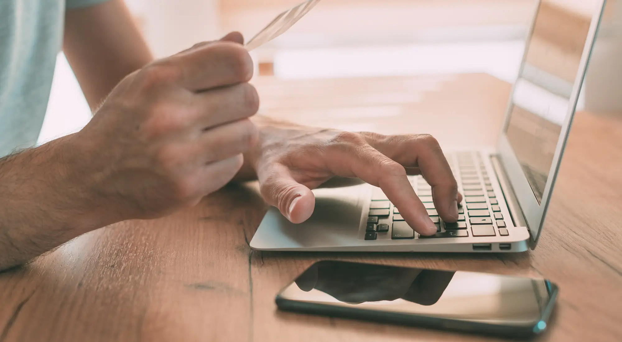 A person paying a bill online with a card and laptop