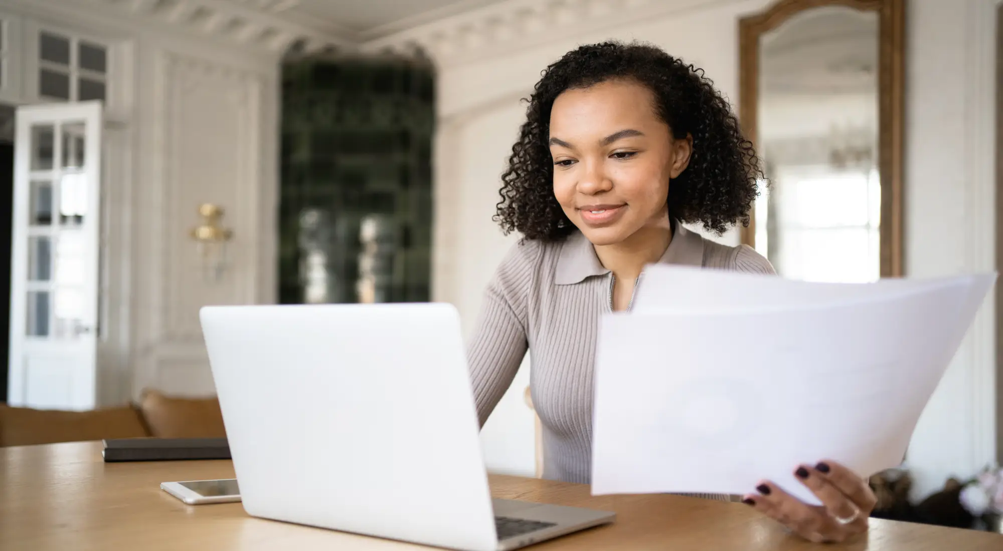 A woman reviewing home loan paperwork at a laptop