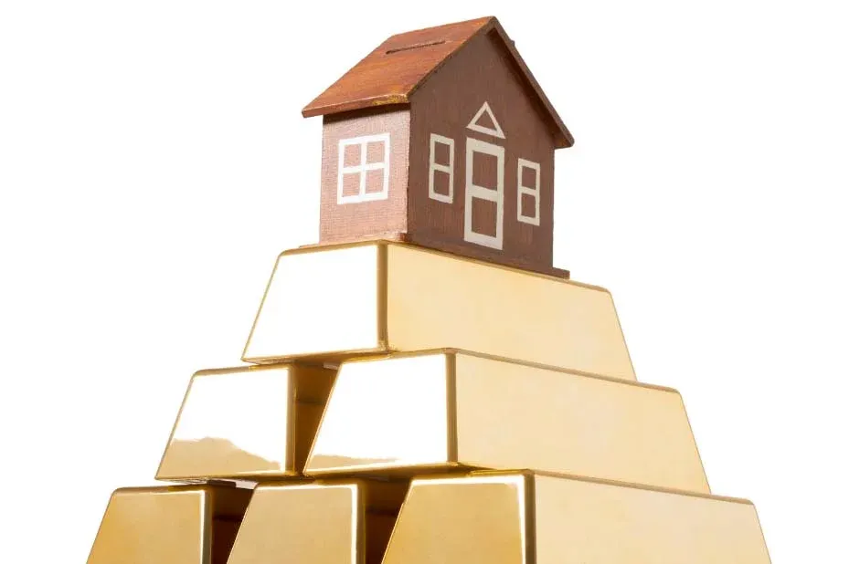 A model house on a stack of gold bars, illustrating value held in a home