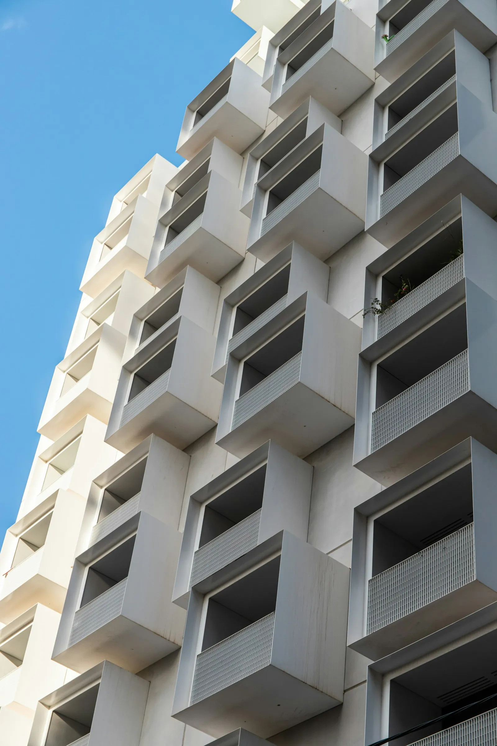 White apartment building with rows of recessed balconies.