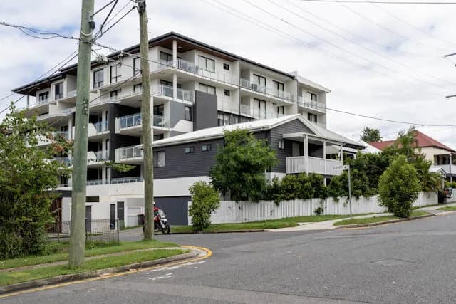 A low-rise apartment building beside older homes on a Brisbane corner