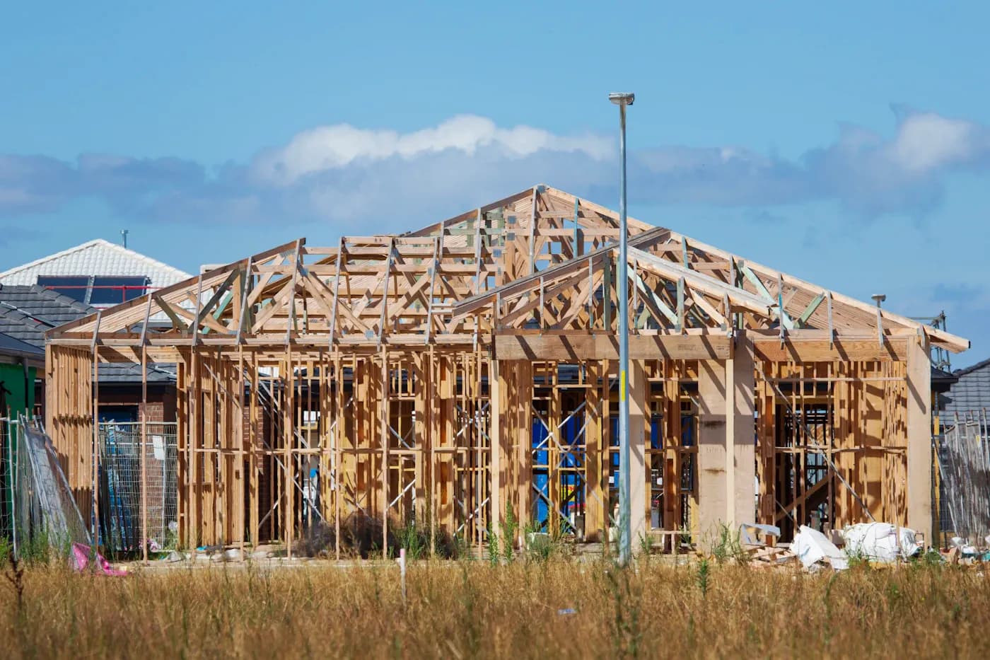 Timber wall frames and roof trusses of a house under construction in Clyde North, Victoria.