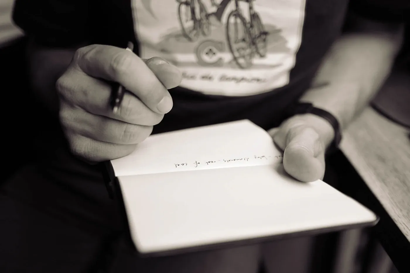 Close-up of hands holding a pen over an open notebook.