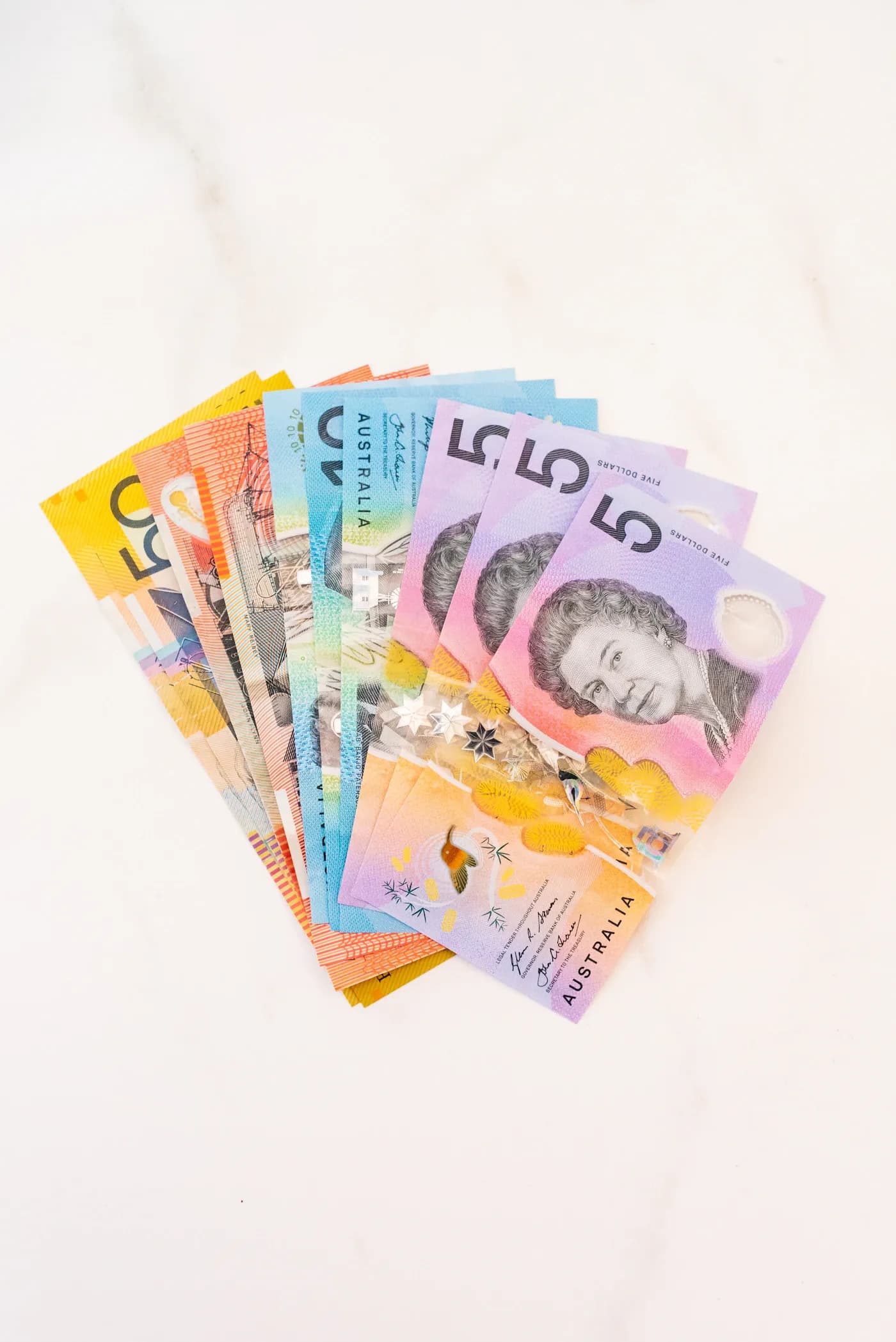 Australian banknotes arranged in a fan on a white surface.