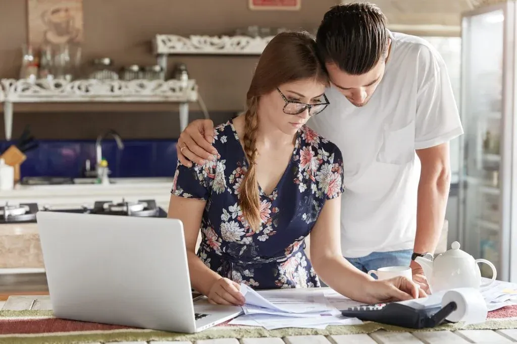 Two people reviewing household paperwork with a calculator