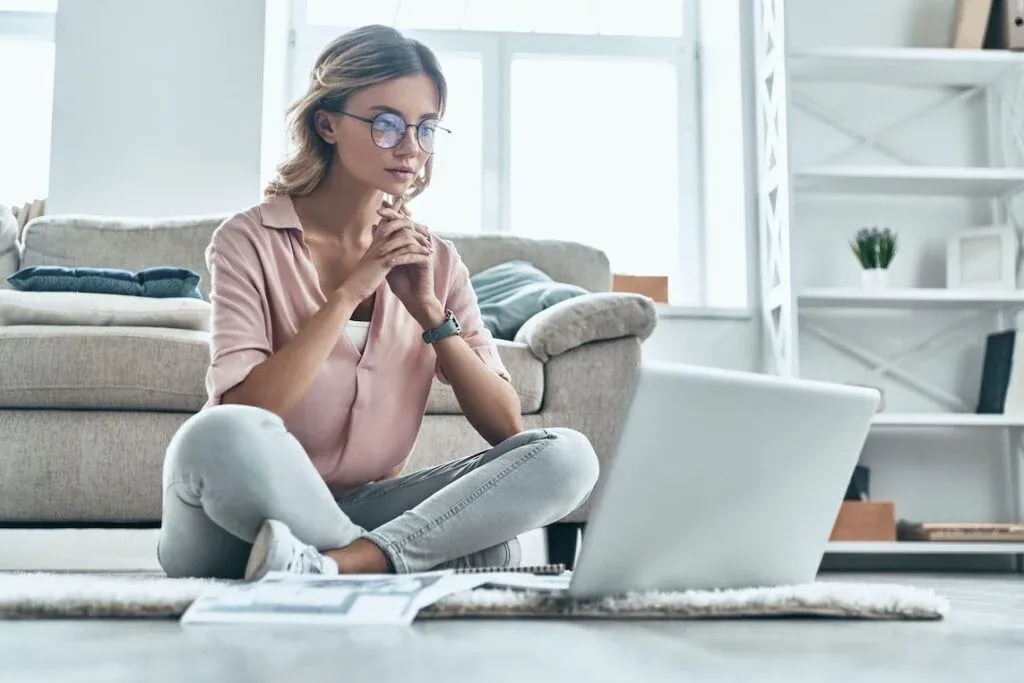 Woman reviewing paperwork and a laptop while seated at home