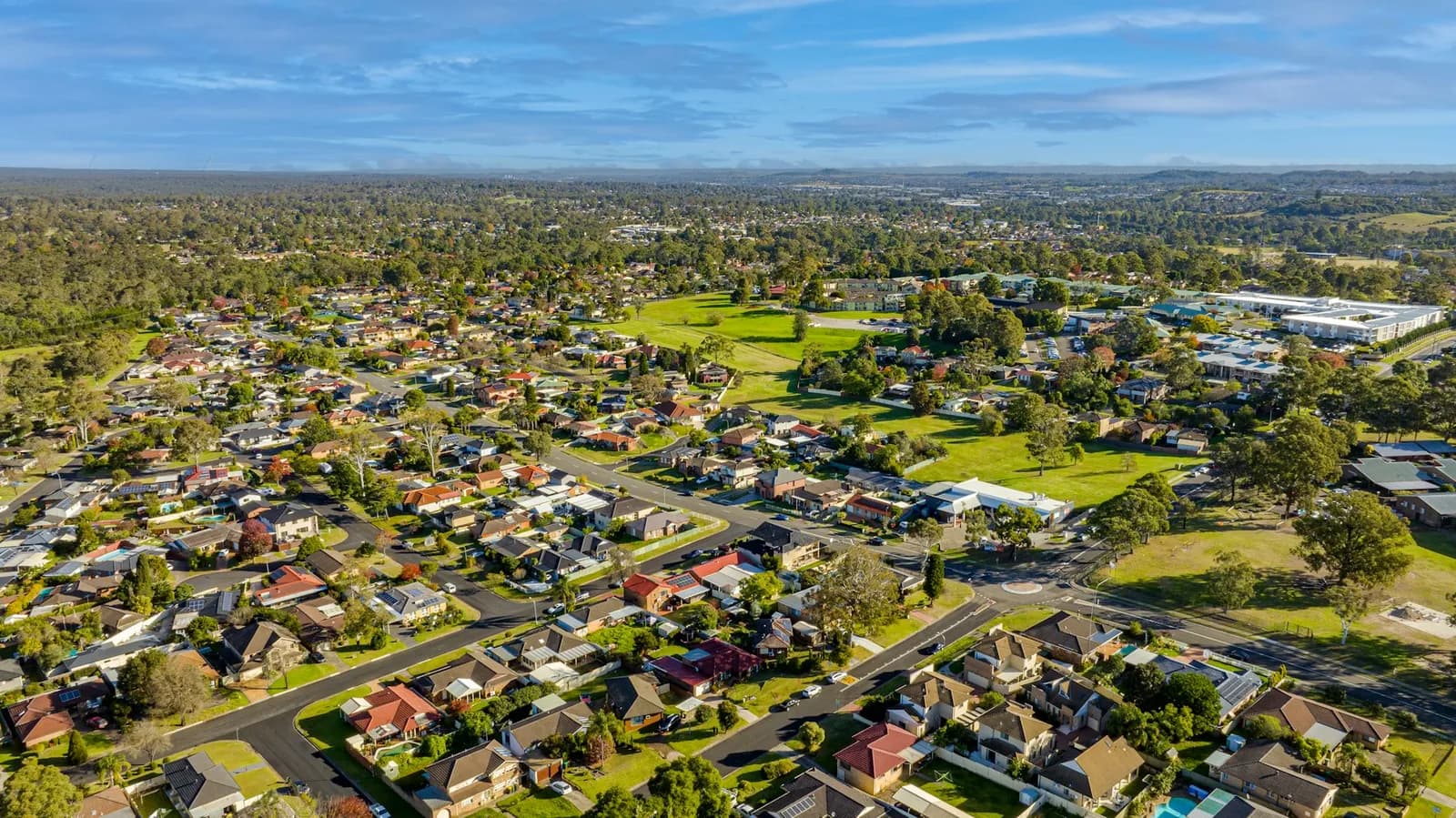 Aerial view of Sydney homes, streets and green parkland.
