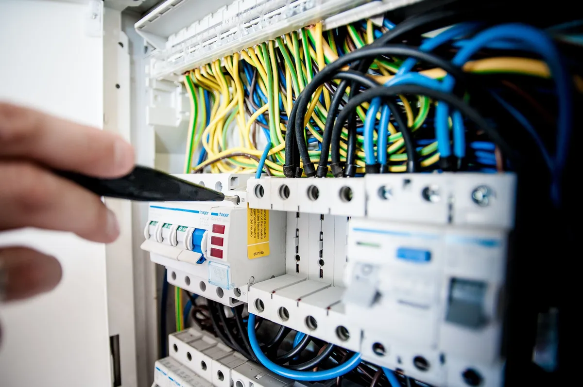 A close-up of an electrician testing wiring inside a circuit breaker panel