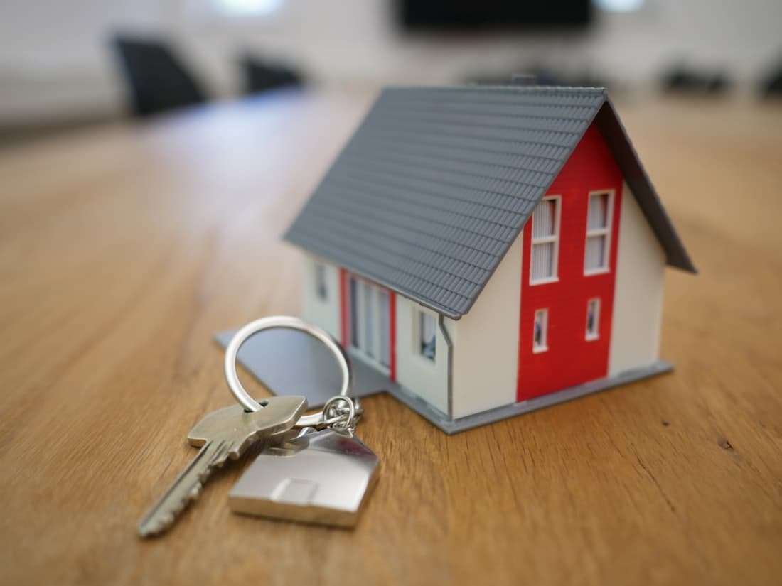 A set of house keys handed over in front of a new home